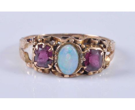 A late Victorian 15ct yellow gold, opal and garnet dress ring, featuring a centre oval cabochon with an oval faceted garnet o