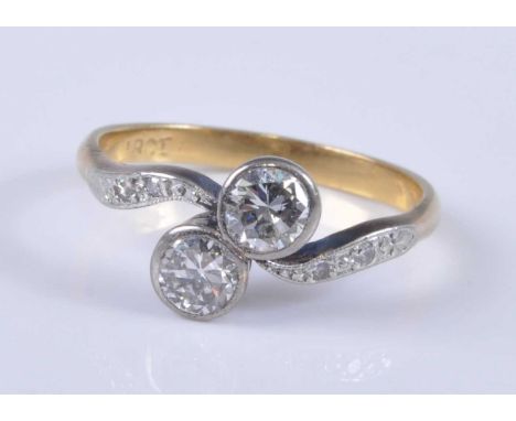 A yellow metal diamond crossover ring, the pair of illusion set round cuts each weighing approx 0.32 carats, the white metal 