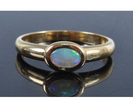 A yellow metal opal dress ring, as an illusion set small cabochon opal measuring approx 4 x 6.5mm, stamped 750 and tests as 1