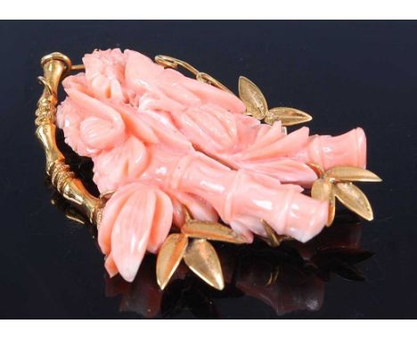 A yellow metal carved pink coral brooch, depicting a bird perching between two bamboo branches, with floral detail and yellow