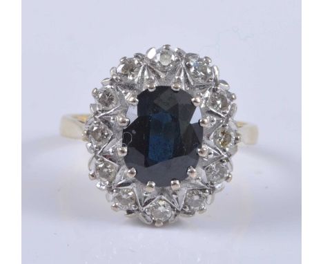 A contemporary 18ct gold, sapphire and diamond cluster ring, the claw set oval cut sapphire measuring approx 9.5 x 7mm, withi