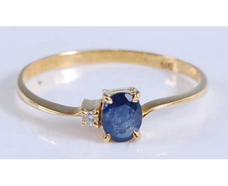 A yellow metal, sapphire and diamond two stone ring, featuring an oval faceted sapphire with a round brilliant cut diamond, a