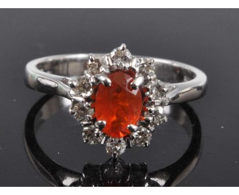 An 18ct white gold, fire opal and diamond oval cluster ring, featuring a centre oval fire opal within a border of ten round b