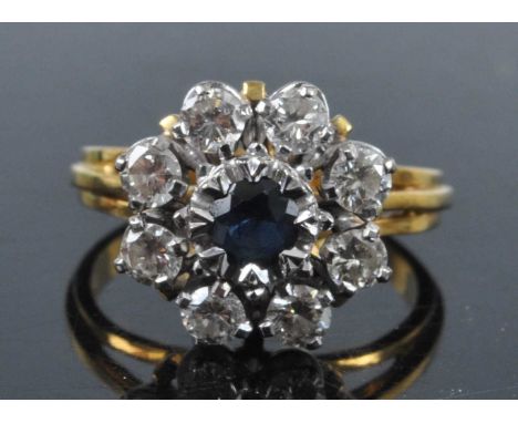 An 18ct gold, sapphire and diamond flower head cluster ring, arranged as a centre sapphire within a surround of eight round b