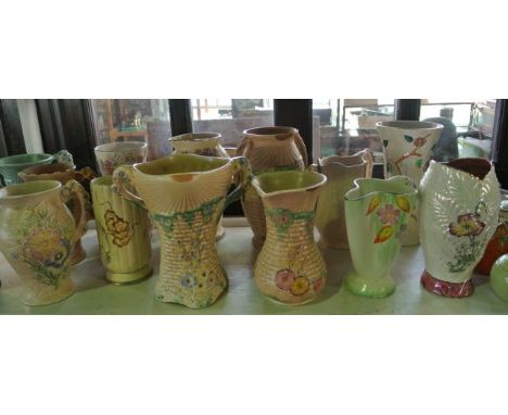 A collection of fourteen jugs and vases by Arthur Wood in various Art Deco style patterns, with relief moulded and painted de