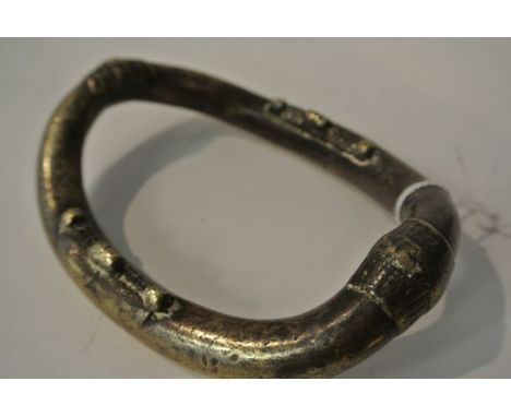 A cast brass bangle, probably African, with applied detail