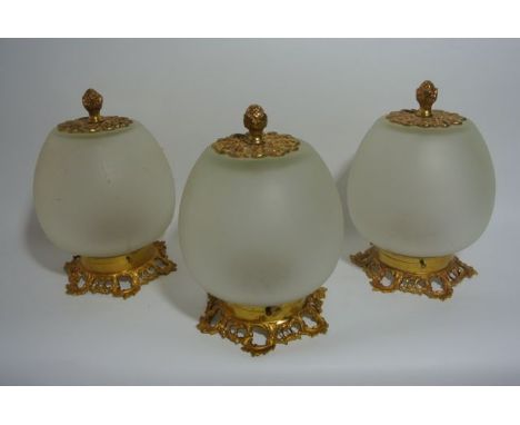 A trio of frosted clear glass light shades of bulbous form with applied ormolu type scrolling metallic mounts with pineapple 