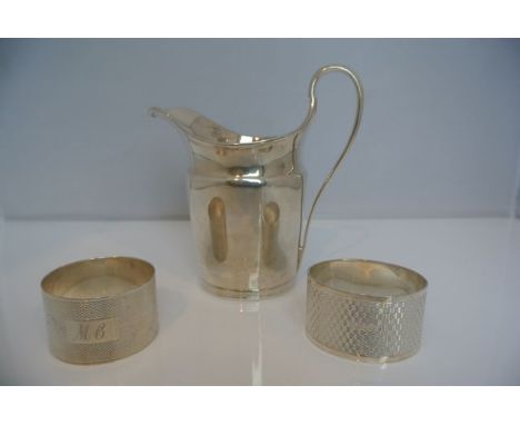 A George III silver milk jug, London, 1798, of plain tapering form, with scroll handle, with crest, 163.5g; and two silver na