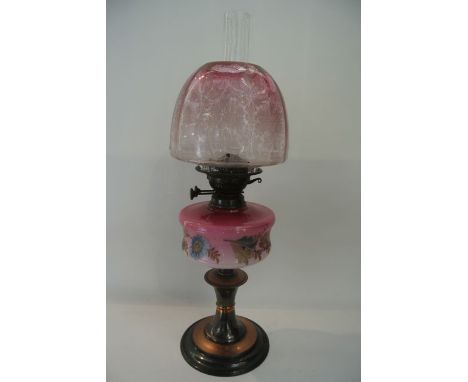 An oil burning desk lamp with an opaque pink glass fount with painted floral decoration and a pink tinted glass shade, clear 