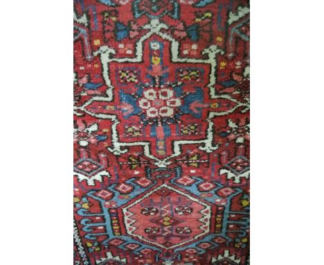 A Persian style wool runner with multi-medallion centre upon a red field within running borders, 175 x 60 cm 