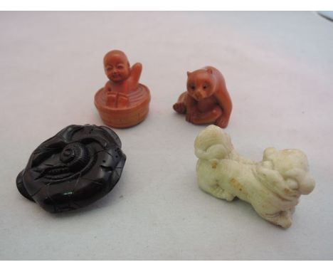 Three carved wood netsuke, a bear cub, child in a bath tub and a snail upon a leaf together with a small carved stone temple 