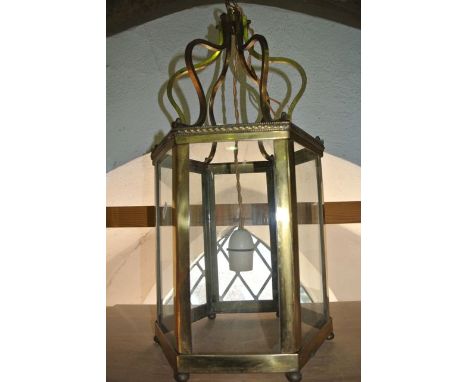 A six sided brass framed  lantern shaped ceiling light with glazed panels with embossed and beaded decoration to the borders,