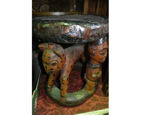 An unusual African carved timber stool of cylindrical form with simple dish top, the two carved supports in the form of stand