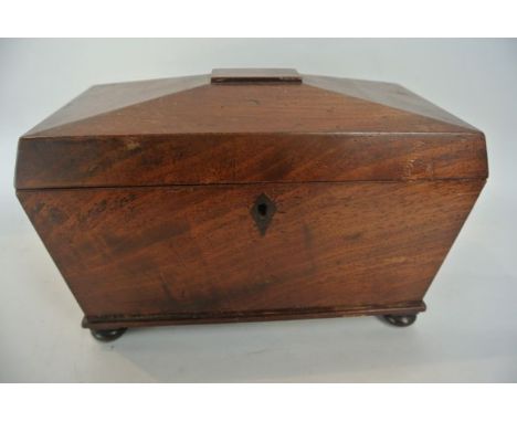 A 19th century mahogany veneered sarcophagus shaped tea caddy raised on four squab supports with hinged lid enclosing a two l