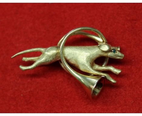 An 18k pin brooch, modelled as a running hound leaping through a French Hunting horn, hound set green jewelled eye, weight 7g