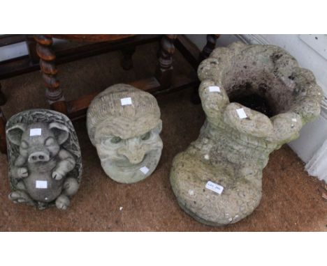 A cast garden planter in the form of boot together with a recumbent pig and a mask