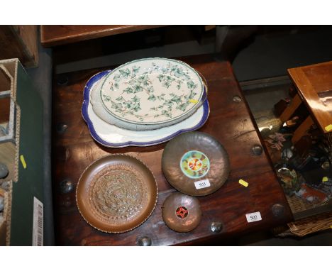 A shallow copper dish; two copper and enamel decorated dishes and three meat platters 