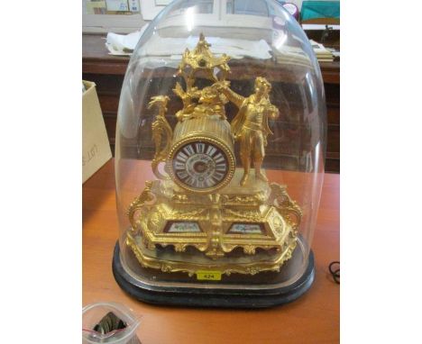 A late 19th century gold painted spelter mantle clock, decorated with a figure, a floral porcelain dial and panels under a gl