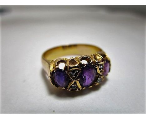 A Victorian yellow metal, three stone amethyst ring flanked by four diamond chips, marks rubbed, 4.2g 