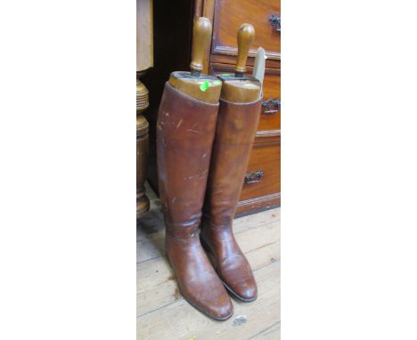 A pair of vintage brown leather riding boots, with wooden boot trees