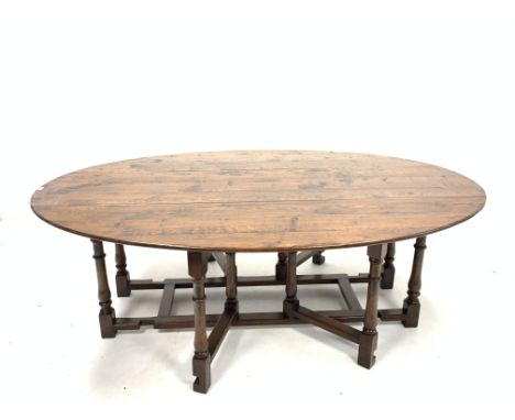 Large 20th century solid oak wake table, the oval top with two drop leaves each raised on turned and block double gate legs, 