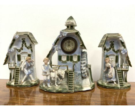 Three piece ceramic  garniture in the form of a water mill, the centre housing a mechanical clock, (W50cm) and another cerami