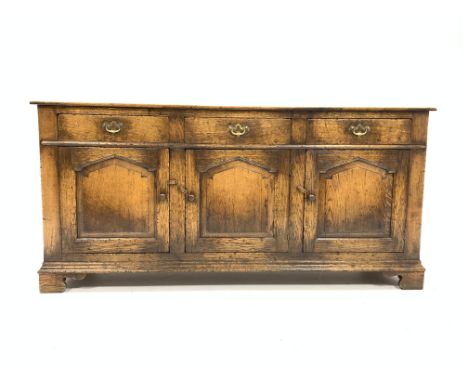18th century style solid oak dresser base, with three drawers over three cupboards, panelled sides, raised on shaped bracket 