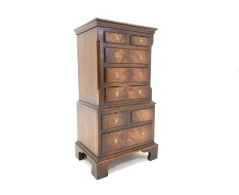 Reprodux mahogany miniature chest on chest, with cross banded top over two short and three long drawers enclosed by canted si