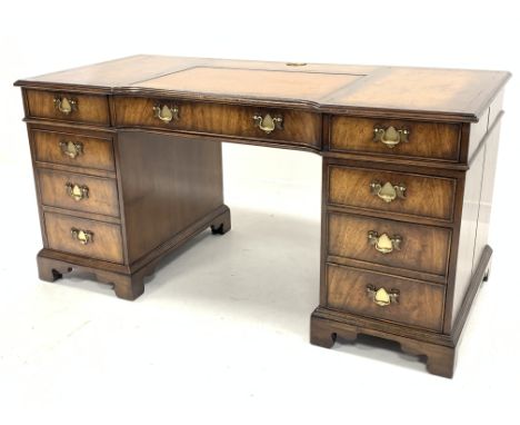 George III style walnut pedestal desk, the inverted breakfront top with inset tooled brown leather writing surface over centr