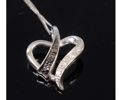 A modern 9ct white gold black and white diamond point set heart shaped pendant on finelink neck chain