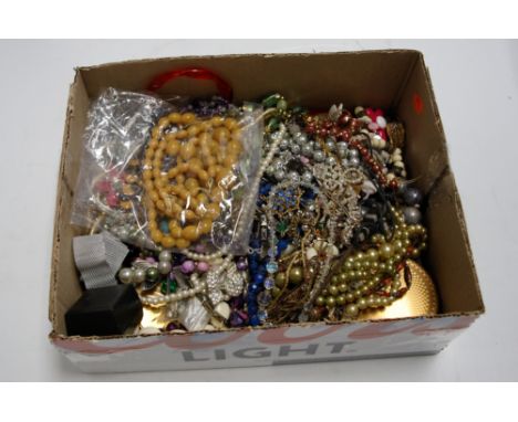 A box of miscellaneous costume jewellery to include faux amber necklace, paste set brooch, ladies compact etc