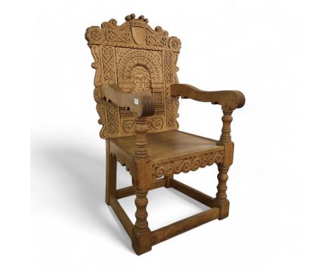 LIGHT OAK ARMCHAIR, with heavily carved detail, on turned supports to stretcher base118cm high