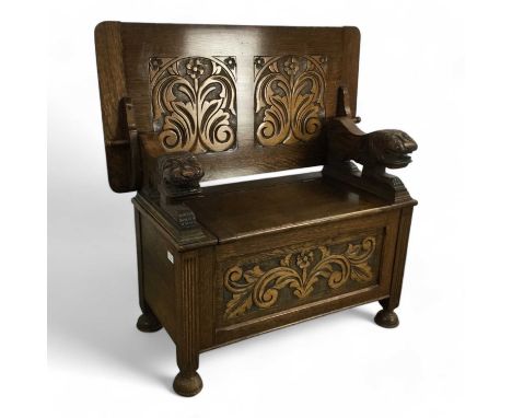 OAK MONK'S BENCH, LATE 19TH / EARLY 20TH CENTURY with carved floral panels and twin arm rests modelled as lions, raised on bu