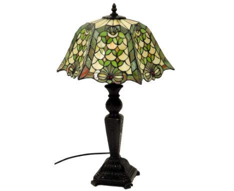 A 20thC Tiffany style table lamp, the leaded glass shade decorated with flowers and leaves in varying shades of green, on a c