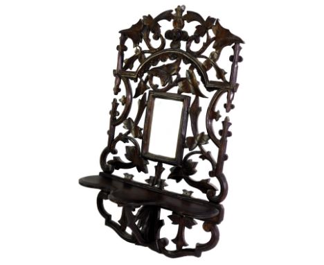 A Victorian carved wooden wall shelf, decorated with leaves, with rectangular mirror panel, above a shaped shelf, 43cm high. 
