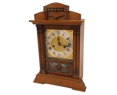 An early 20thC oak cased mantel clock, the carved cornice with a central crest and beaded decoration, on two columned support