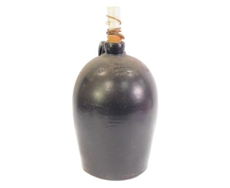 A 19thC black painted stoneware flagon for Mills Newzam and Althorp, Druggists Stamford, converted to a table lamp, not drill