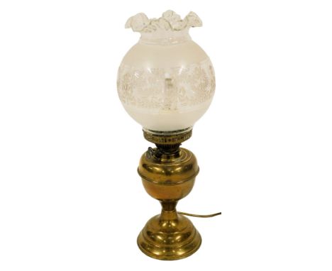 An early 20thC oil lamp, the frosted and clear glass shade decorated with bows, swags, etc., on a brass base, converted to el