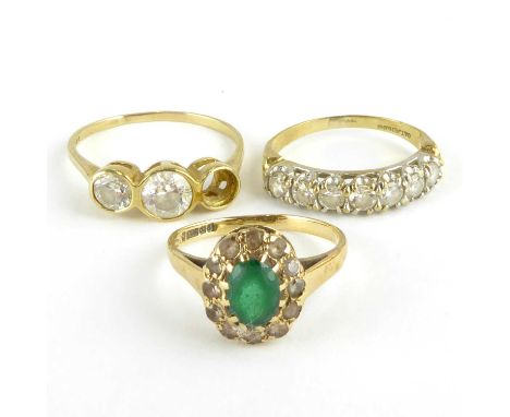 Three 9ct gold dress rings comprising a half eternity ring claw set with seven white stones, size K, one with central green s