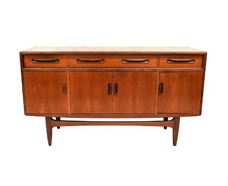A 1960s teak sideboard with three frieze drawers above a pair of panelled doors flanked by two further doors, raised on round