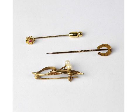 A 9ct yellow gold horseshoe stick pin, a yellow metal leaf brooch with two small pearls, and a yellow metal floral stick pin 