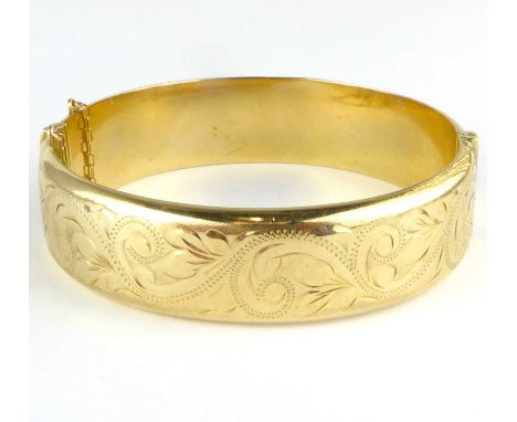A 9ct gold hollow hinged bracelet with safety strap, floral swirls to one half, length 6cm, approx. 19.7g.Condition Report: B