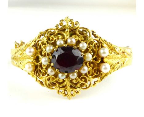 An early 20th century 14ct gold fancy bracelet with claw set cut red stone within a ring of small seed pearls, in an openwork