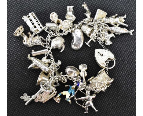 A hallmarked silver charm bracelet united with a heart-shaped padlock clasp, with approximately twenty-nine small charms, to 