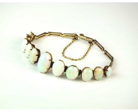 A yellow metal graduated opal bracelet, designed as eleven oval cabochon opals claw set in yellow metal and attached to yello