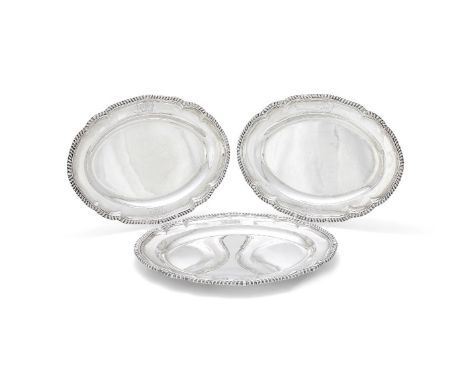 A set of three late George III silver shaped oval graduated serving plates by Robert Garrard I, London 1815, with raised gadr