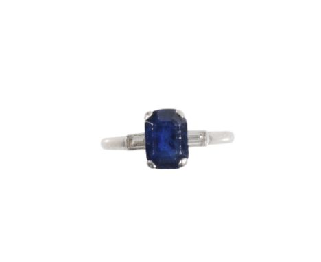 AN ART DECO SAPPHIRE AND DIAMOND RING, the rectangular cut sapphire in a four claw setting, between baguette cut diamond set 