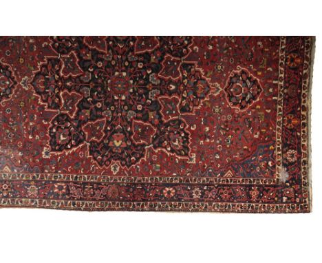 LARGE BAKHTIARI STYLE CARPET, Central Persian, with a large dark blue central medallion, on a red ground populated with styli