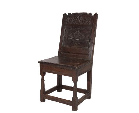 CARVED OAK WAINSCOT CHAIR, basically third quarter 17th century, the back rest with scroll-carved top rail above stylised fol