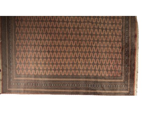 BOKHARA STYLE CARPET, Central Asian Turkmen influence, with all over repeated gul motif, faded brick red ground, 325cm x 252c